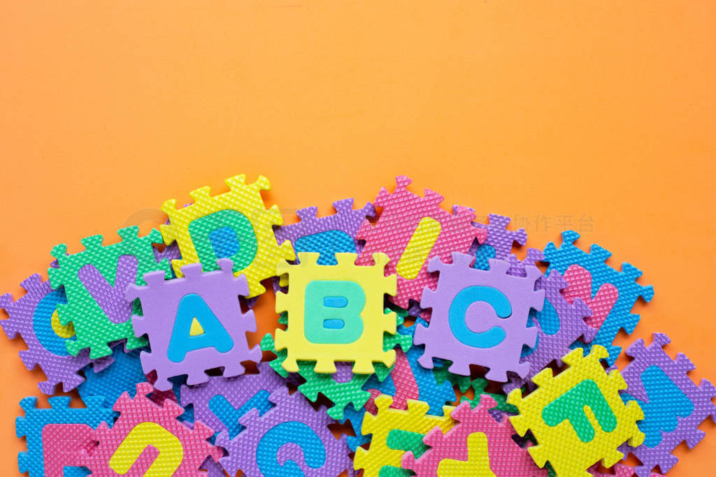 Alphabet puzzle on orange background.