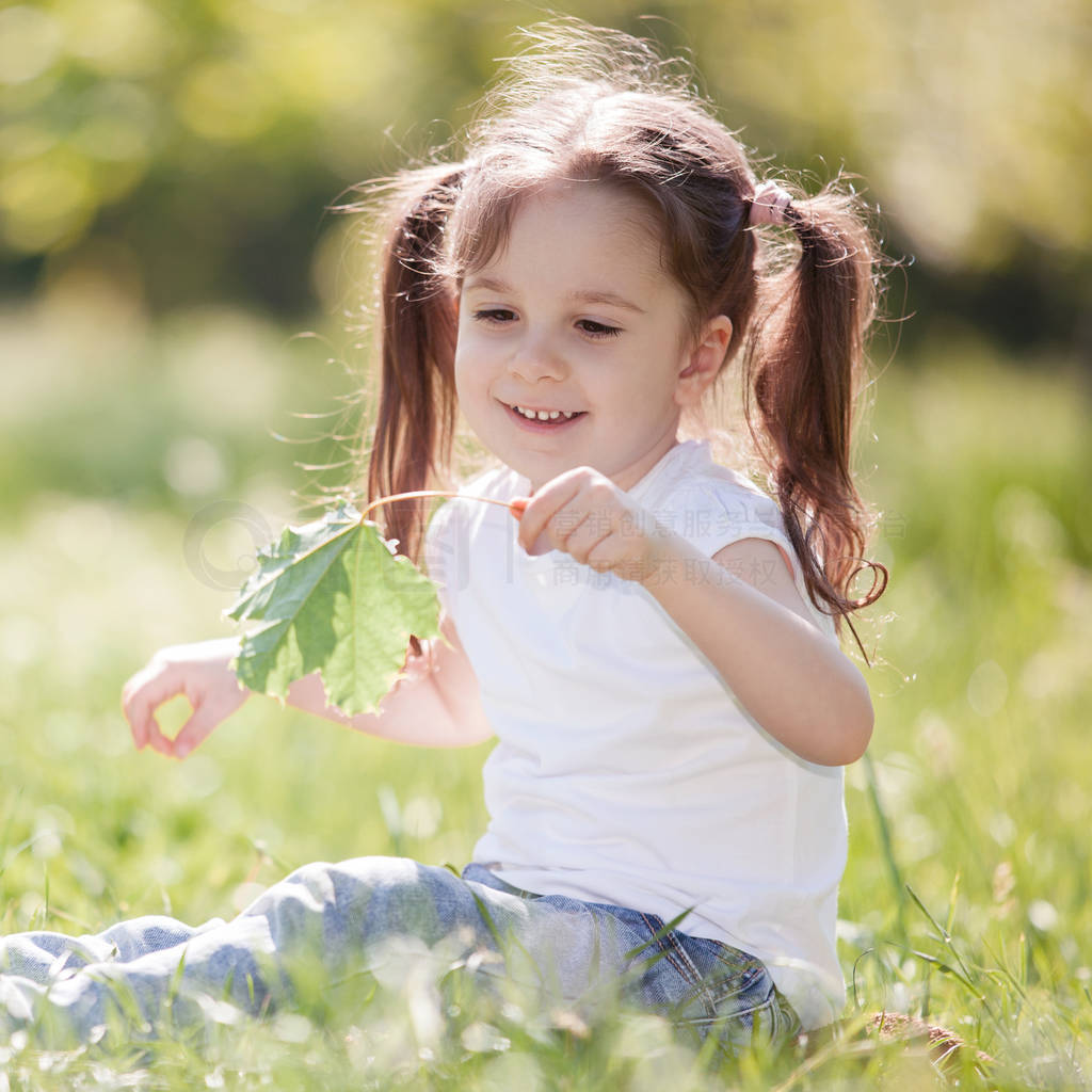 Cute little girl play in the park with leaves and flowers. Beaut