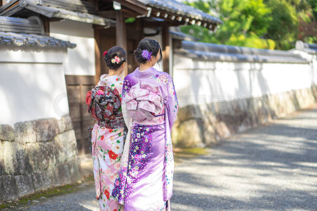 Geishas girl wearing Japanese kimono among red wooden Tori Gate