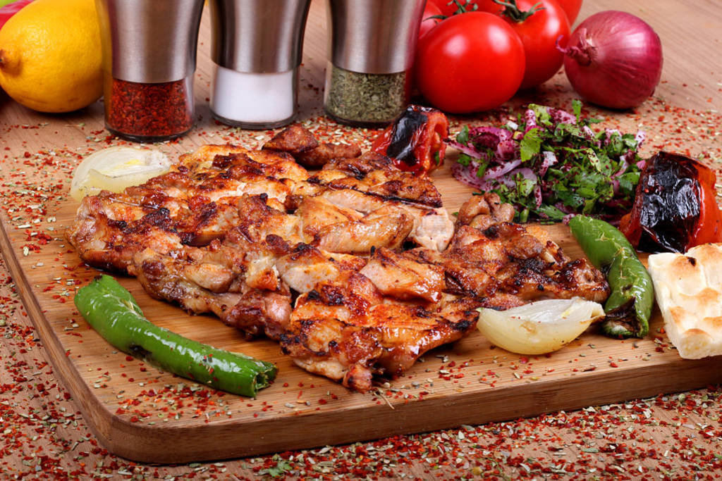 Grilled chicken service on a white plate on a wooden table full