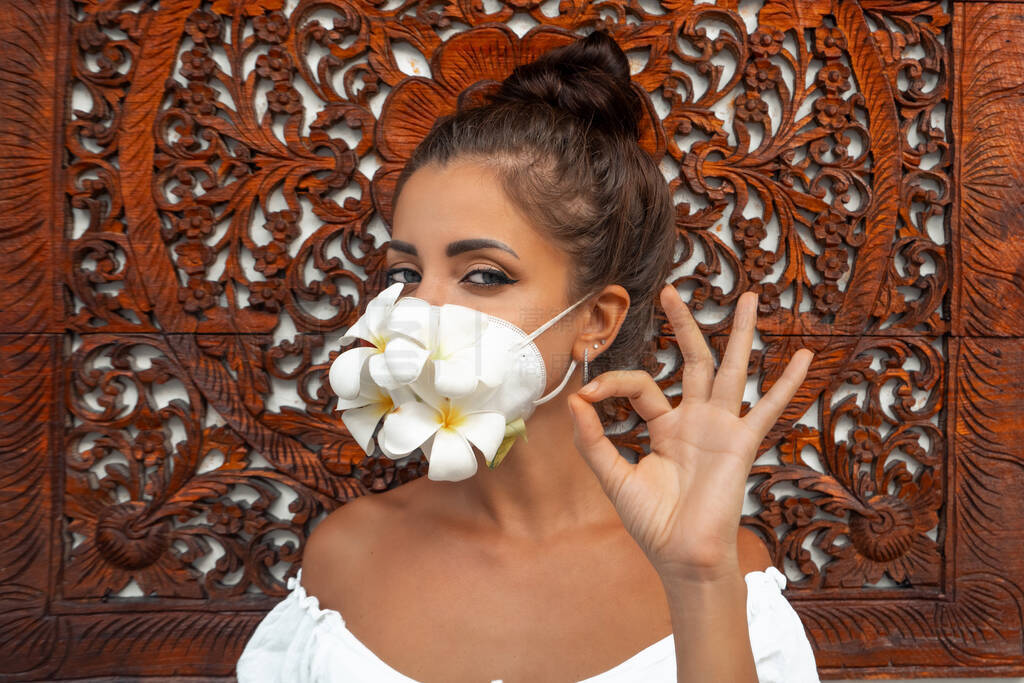Girl in a mask of fresh flowers. Hand gesture depicts all is we
