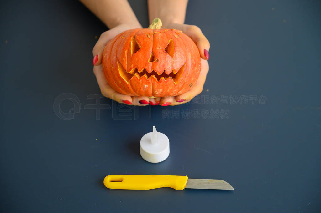 Woman holds a little pumpkin over black background. Halloween c