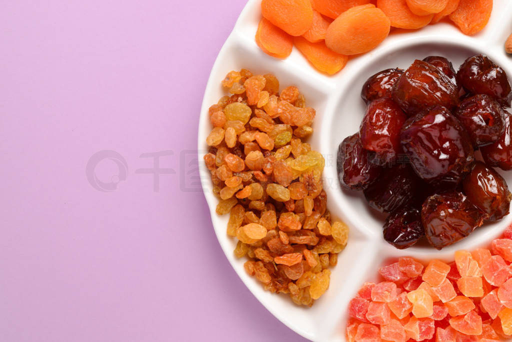 Mix of dried fruits and nuts on a white plate. Apricot, almond,