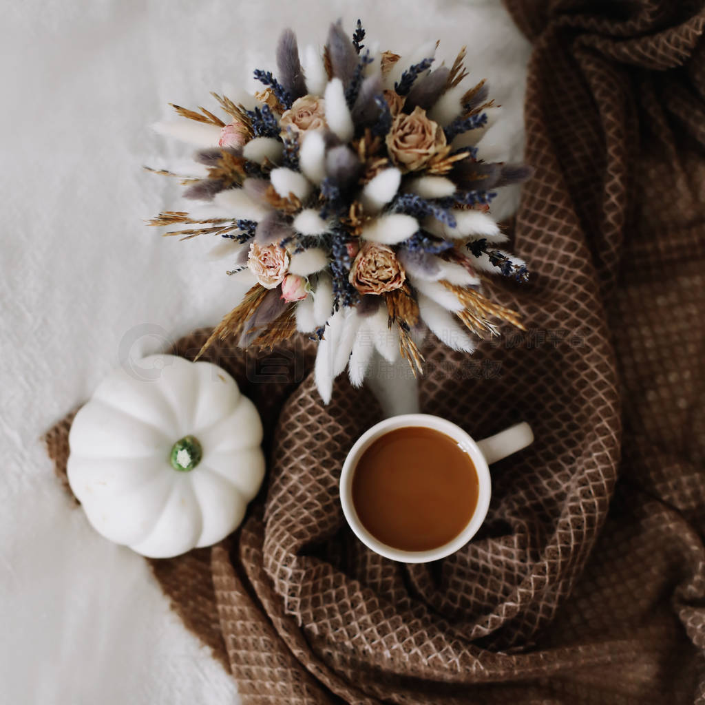 Coffee cup with flowers and pumpkins on a cozy plaid. Autumn sti
