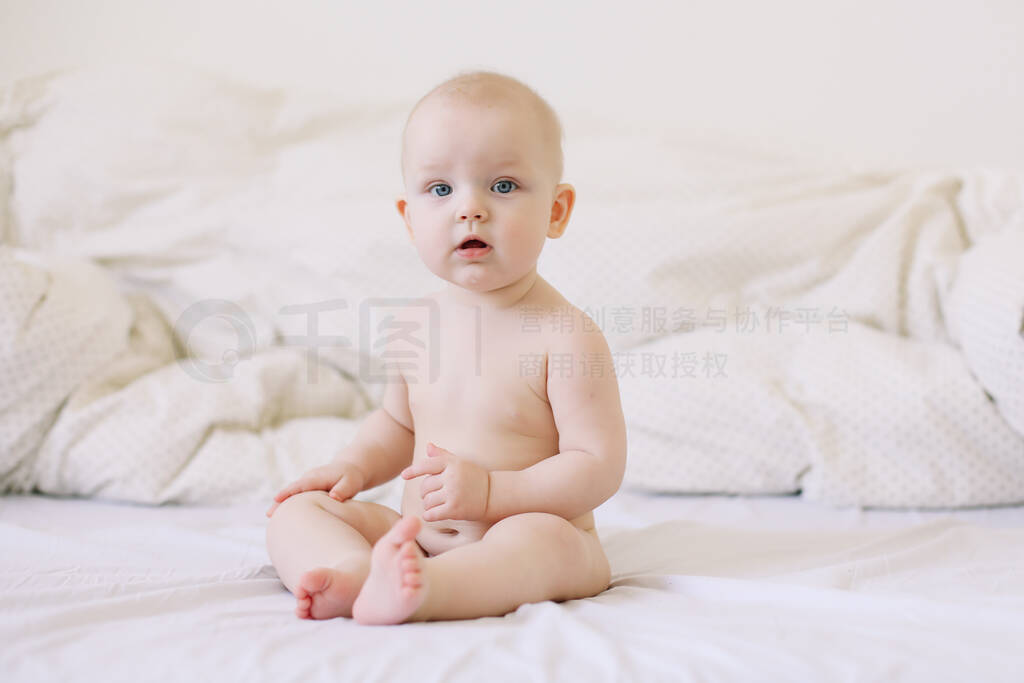 Cute smiling baby sits on the bed. happy naked baby. children u