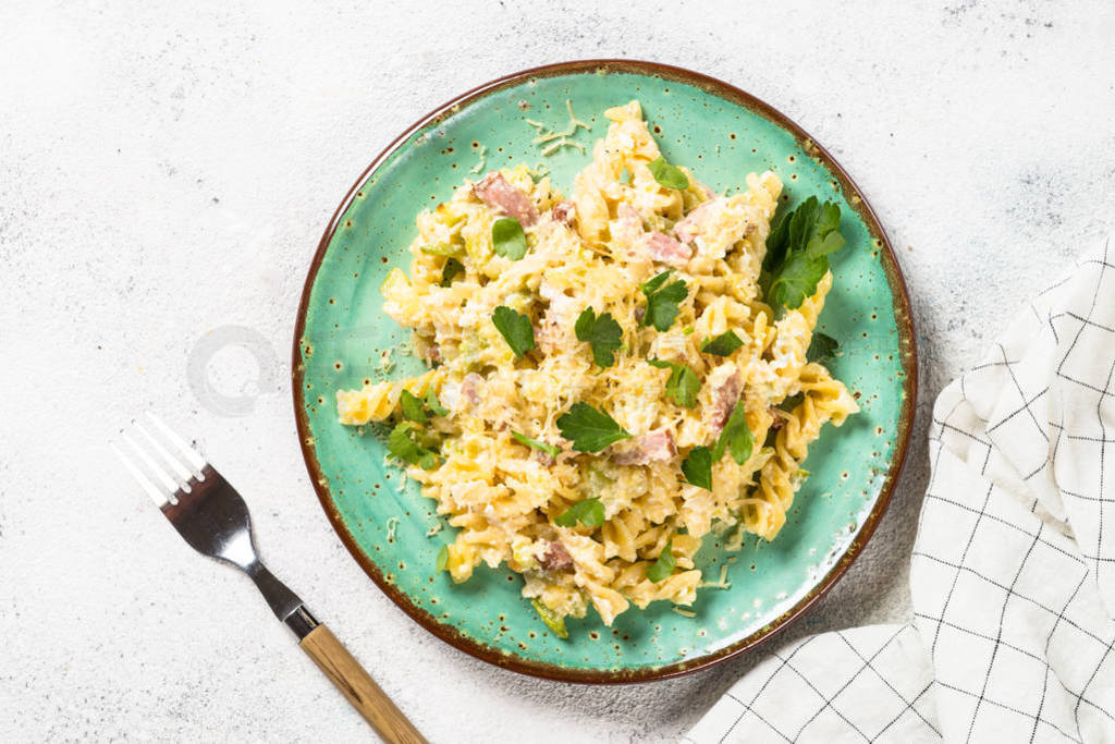 Pasta carbonara with zucchini in craft plate on white.