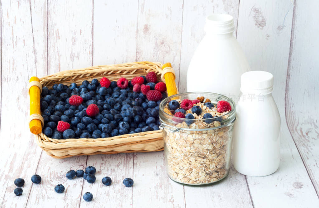 Muesli with blueberries in glass jar on white wooden background.