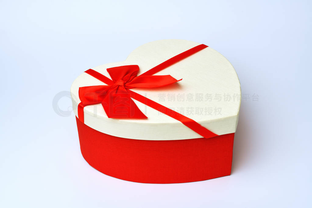 Box. Heart-shaped gift box with red ribbon stands in the middle