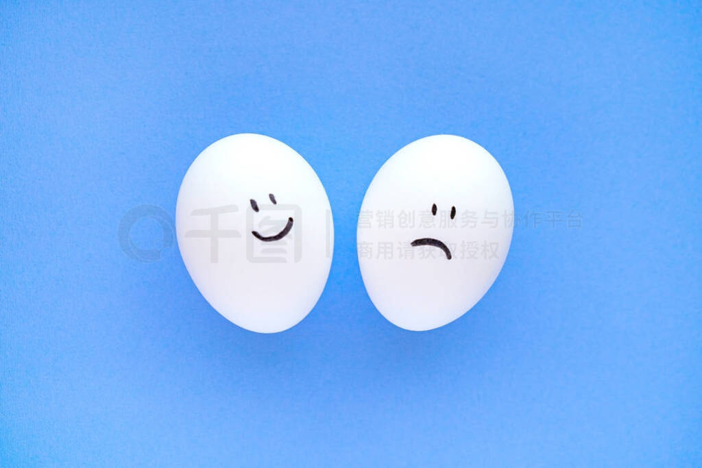 White eggs with emoticons of sadness and joy on a blue backgroun