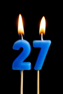 燃烧蜡烛的形式为27二十七 (数字, 日期) 的蛋糕孤立的黑色背景