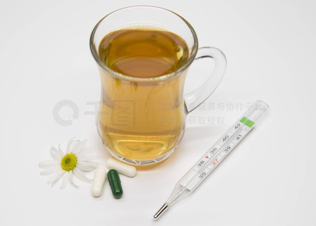 Herbal tea in transparent Cup, thermometer and white pills.