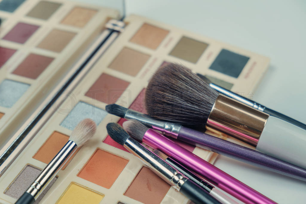 Cosmetics products, brushes and palette on a white surface