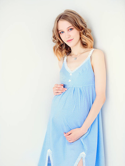 年轻, 孕妇穿着蓝色的衣服在白色的背景怀孕和母性孕妇时尚