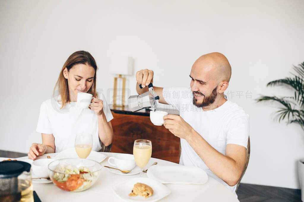 Young happy couple having breakfast at home together