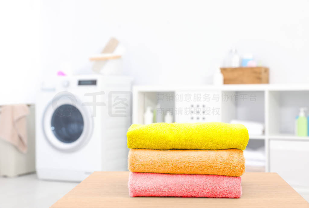 Colorful clean towels on table in laundry room, space for text