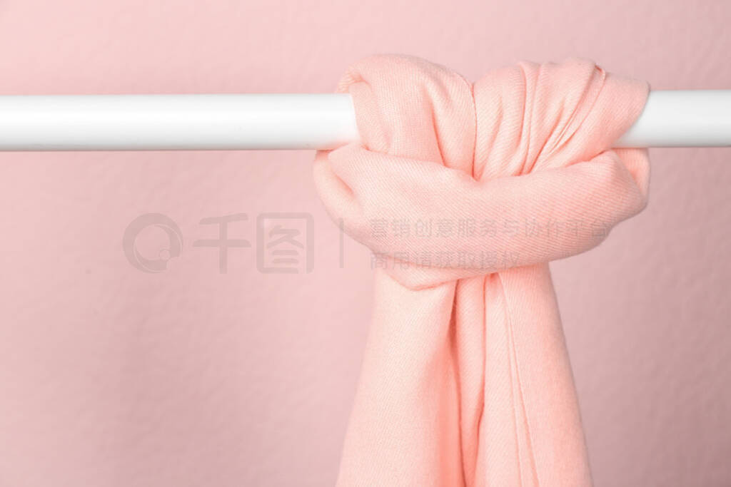 Elegant scarf on wardrobe rack against pink background, space fo