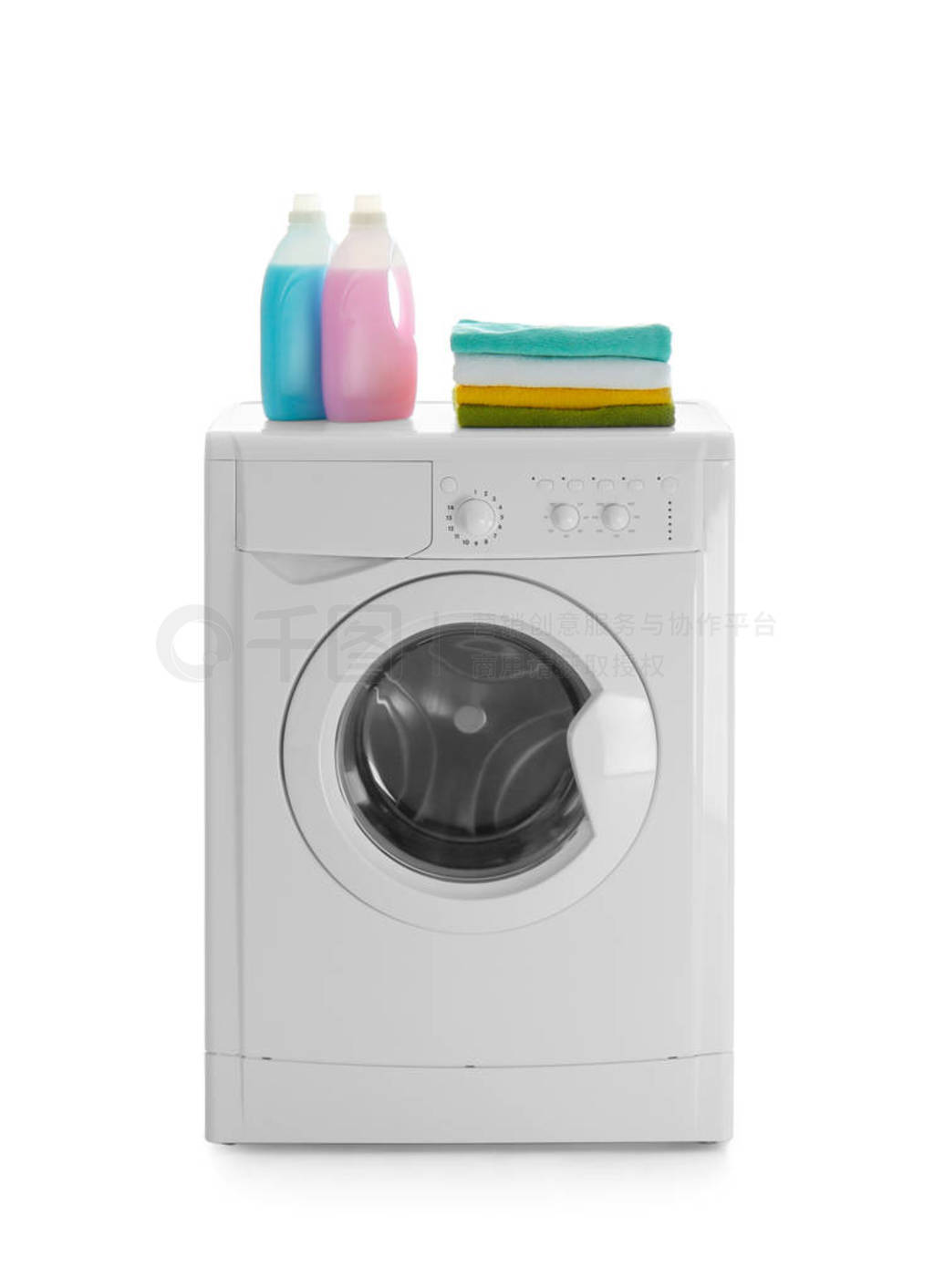 Modern washing machine, stack of towels and detergents on white