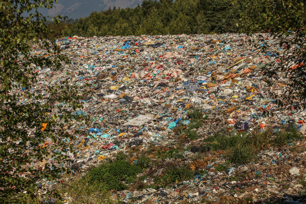 Landfill / dump site surrounded by green trees and mountains in