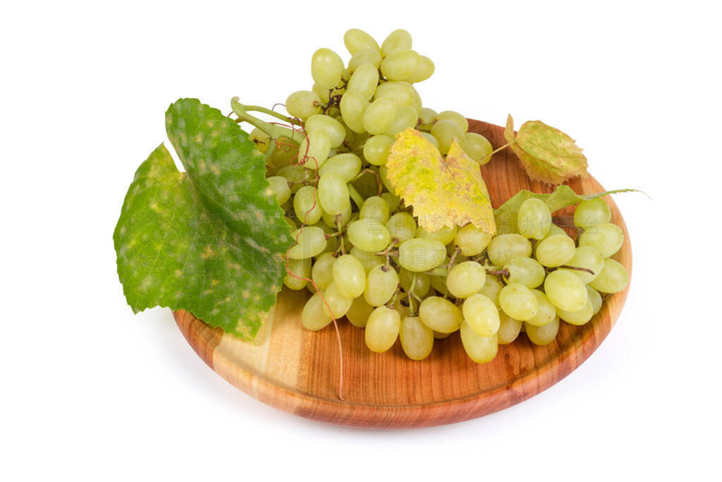 Sultana grape cluster with vine leaves on vintage wooden dish