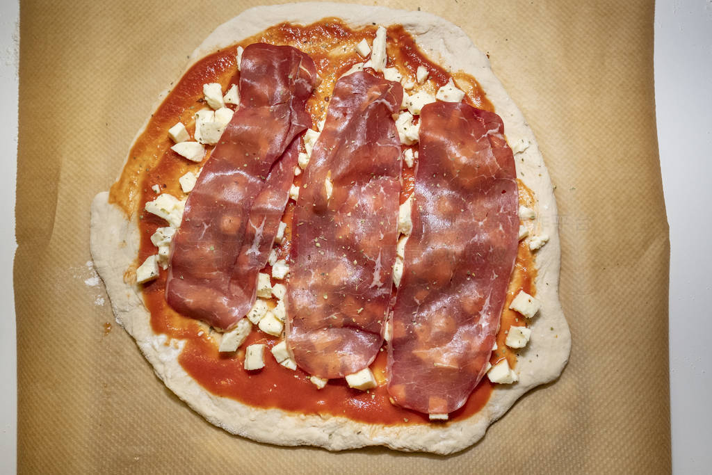 homemade pizza dough with tomato sauce and mozzarella on baking