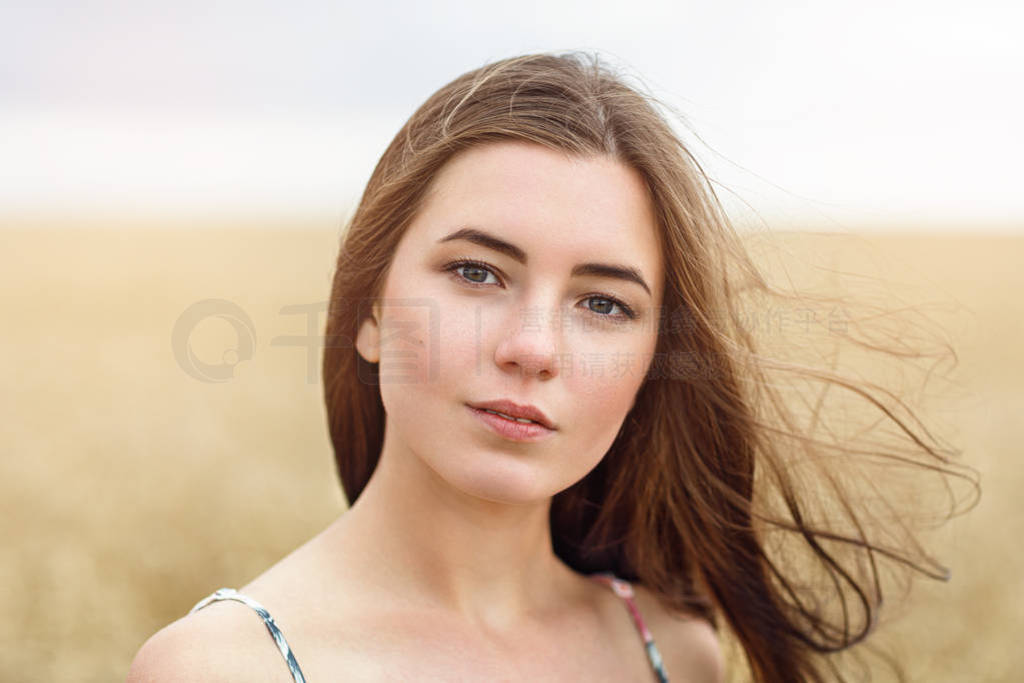 Portrait of the girl posing against the background of the wheat