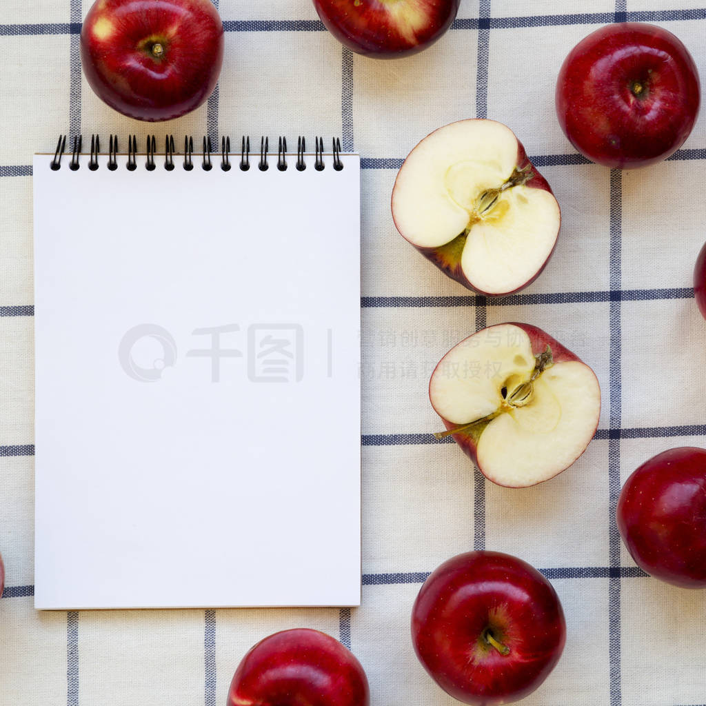 Raw red apples and blank notebook on cloth, overhead view. Flat