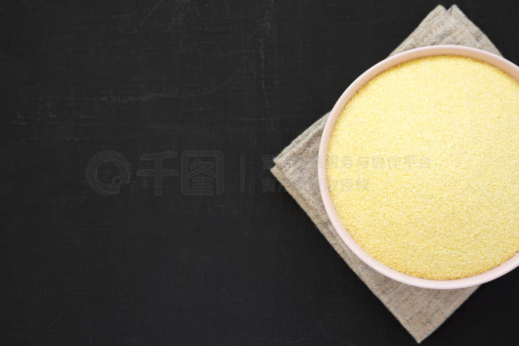 Dry semolina durum flour in a pink bowl over black surface, top