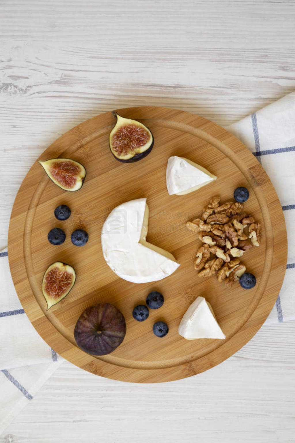 Camembert cheese with figs, blueberries and walnuts on a bamboo