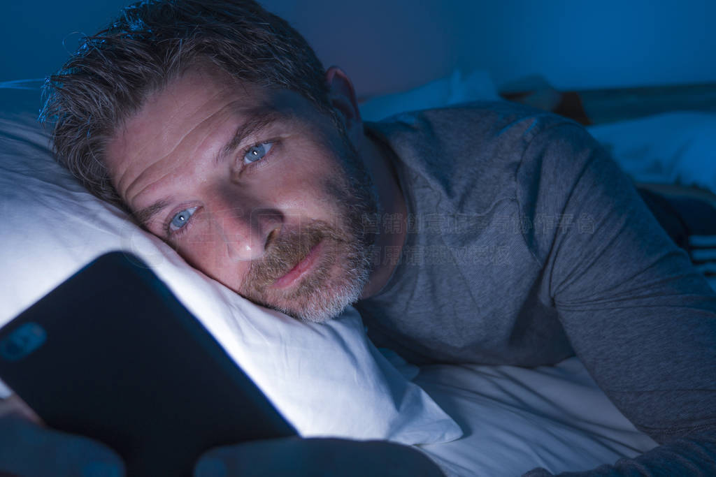 young attractive and relaxed man with blue eyes lying on bed lat