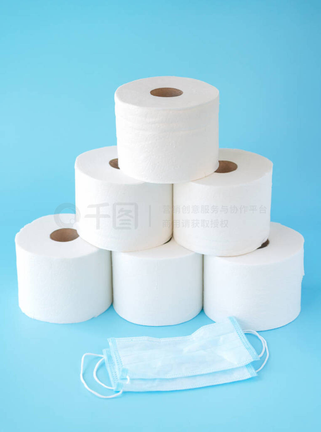 Toilet paper stacked rolls, medicine mask on a blue background.