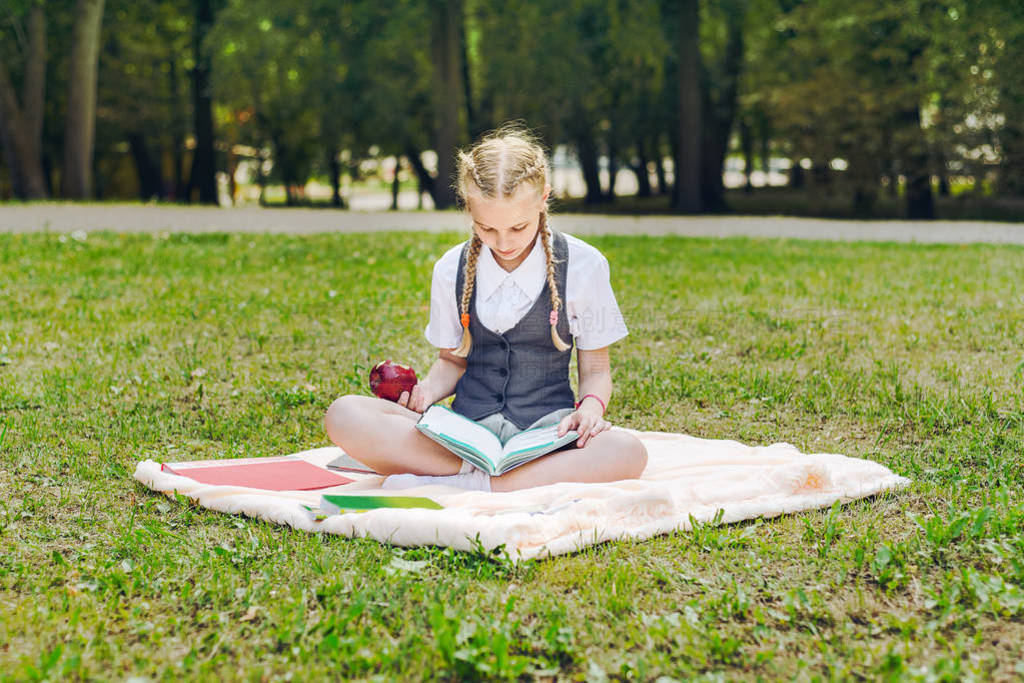 student in uniform eating a red apple for lunch. schoolgirl sitt