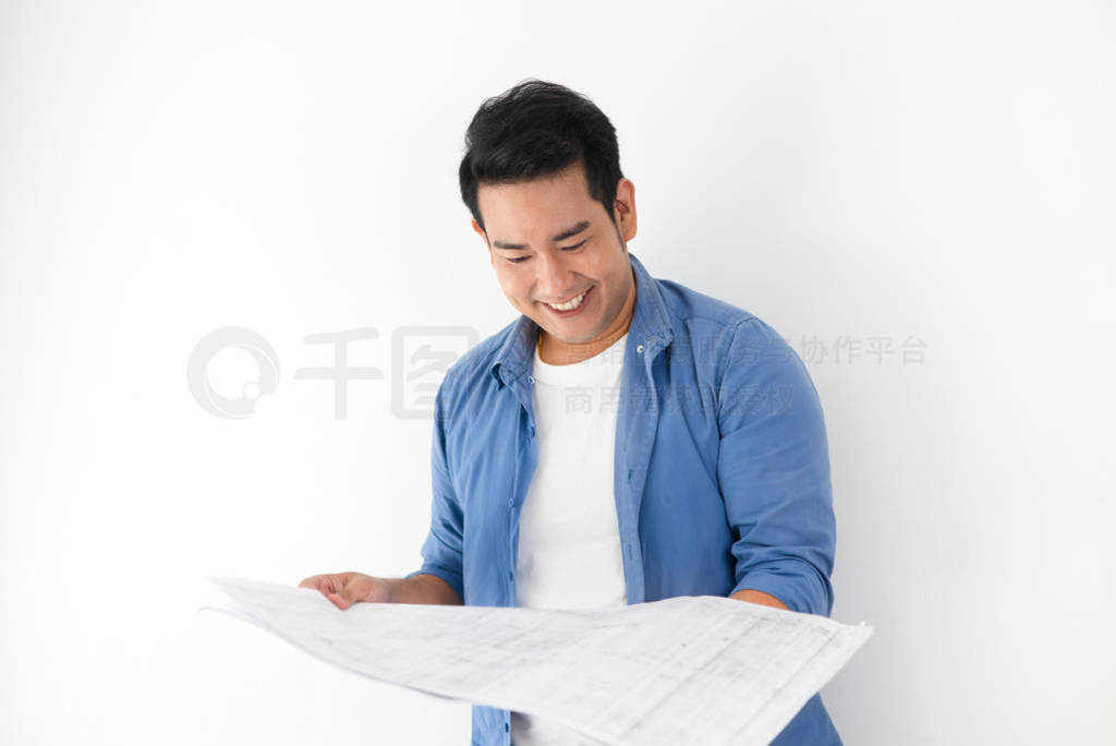 Happy ASian man looking at blueprint in his hands against white