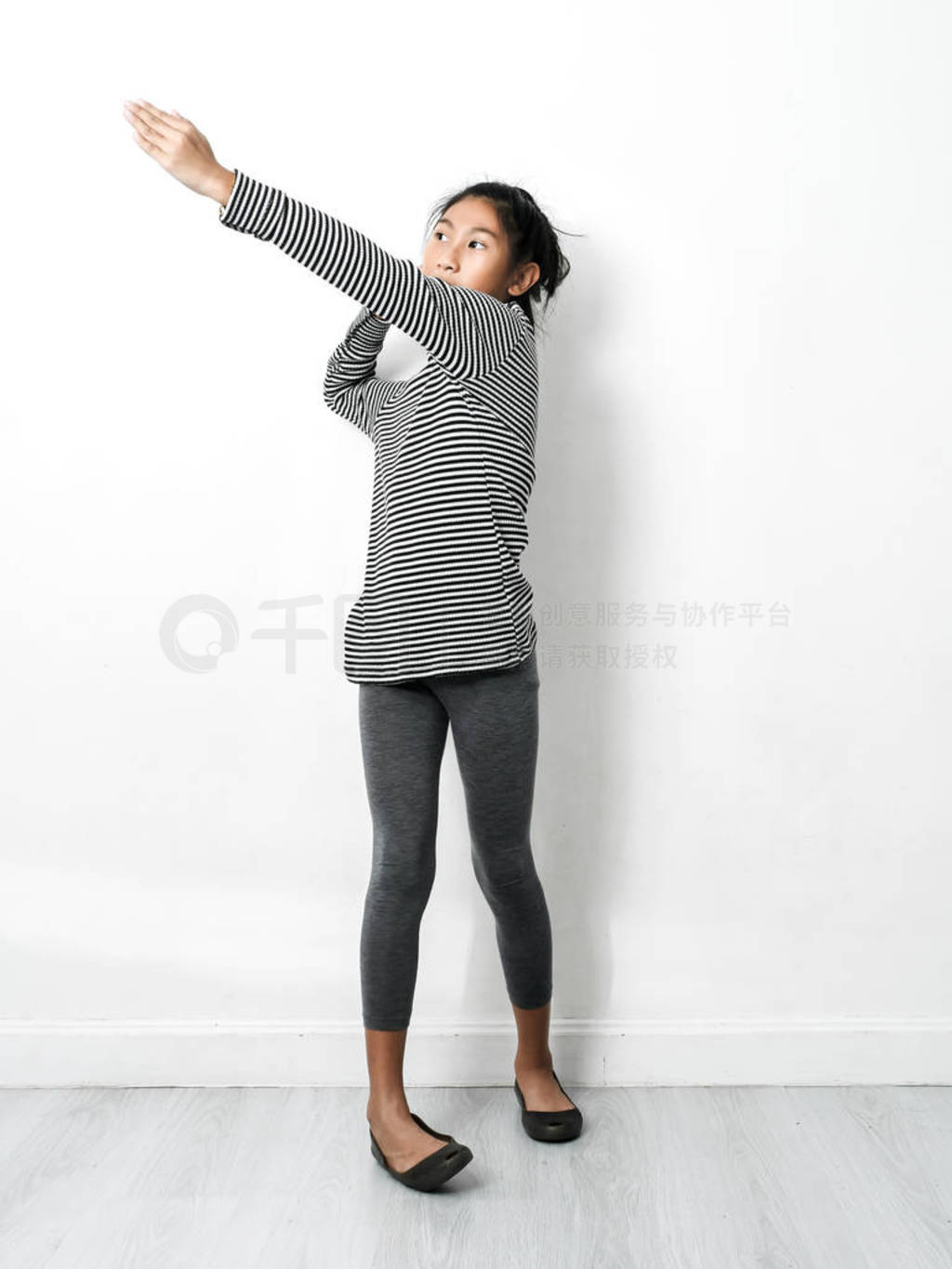 Asian girl wearing turtle neck, skinny dancing with white wall,