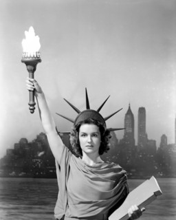 年轻的女人打扮得像自由女神像的背景中的摩天大楼