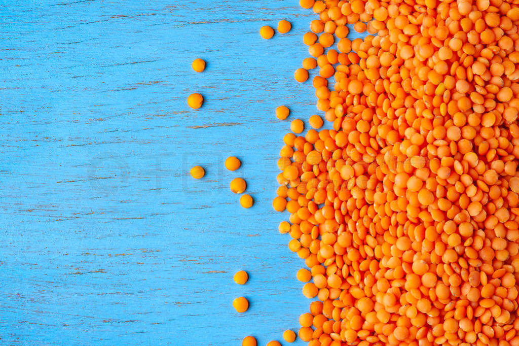 Red lentils on a blue wooden background. Background with a lot o