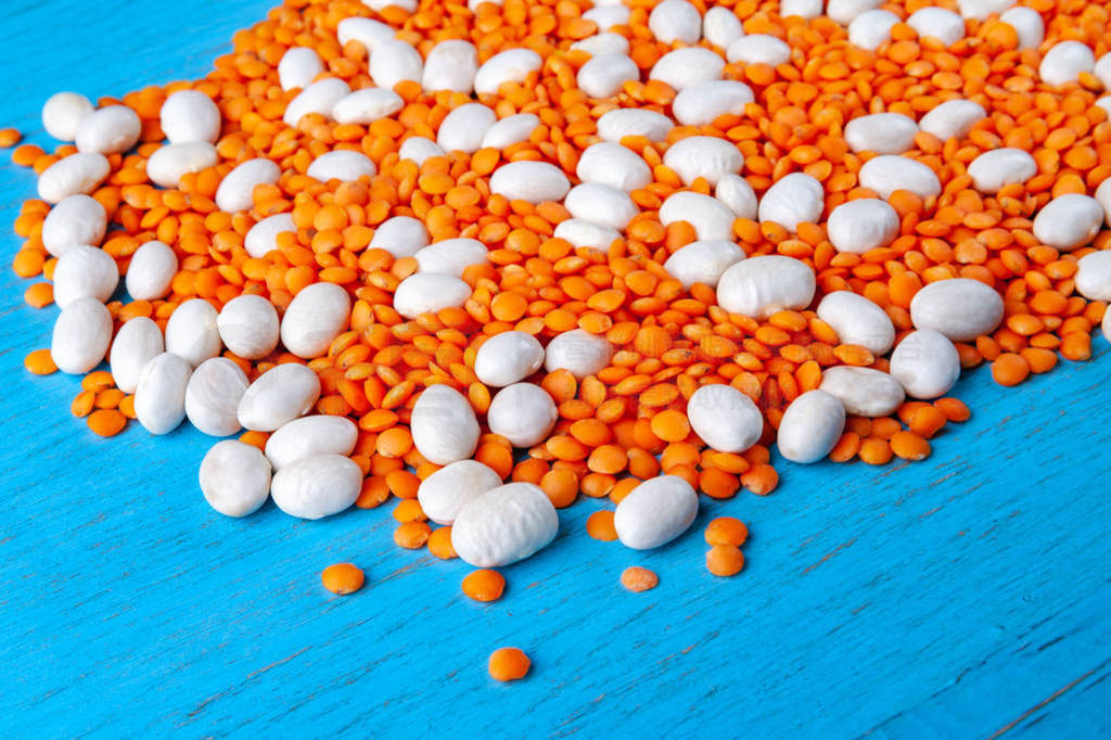 Mixed white beans and red lentils on a blue wooden background.