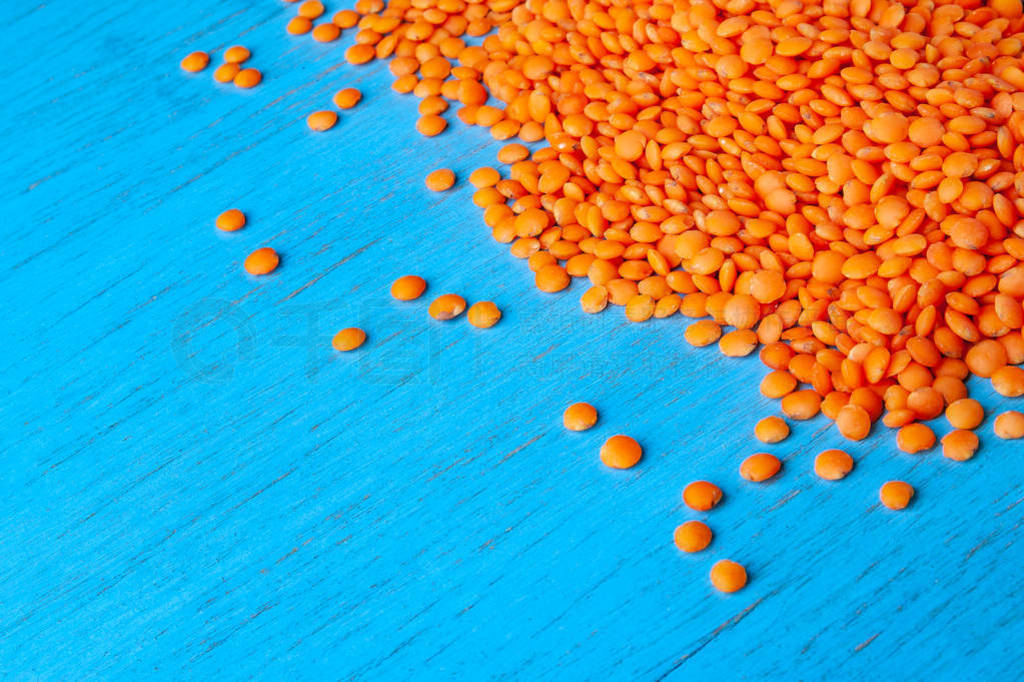 Red lentils on a blue wooden background. Background with a lot o