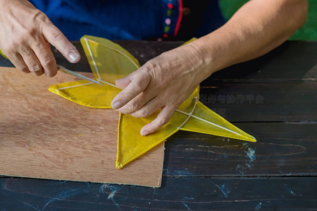Eldery woman making and build star-shaped kite or thai name Chul