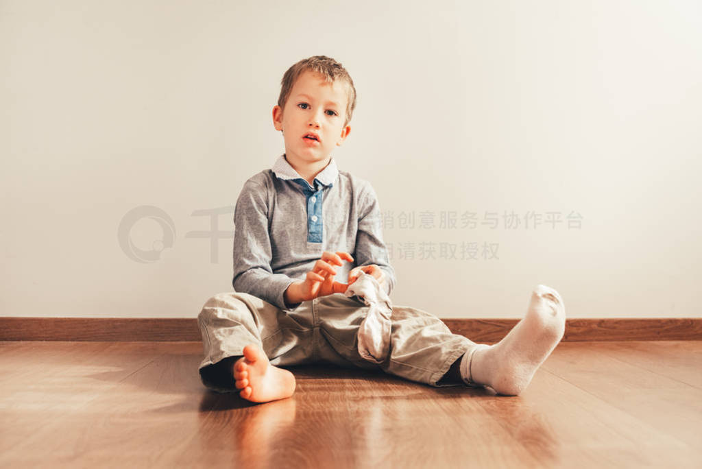 Child with lots of independence sitting on the floor putting on