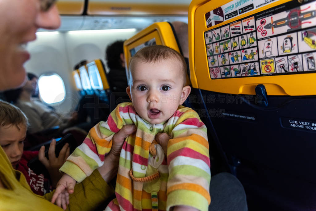 Baby entertaining in the arms of his mother sitting in the seat