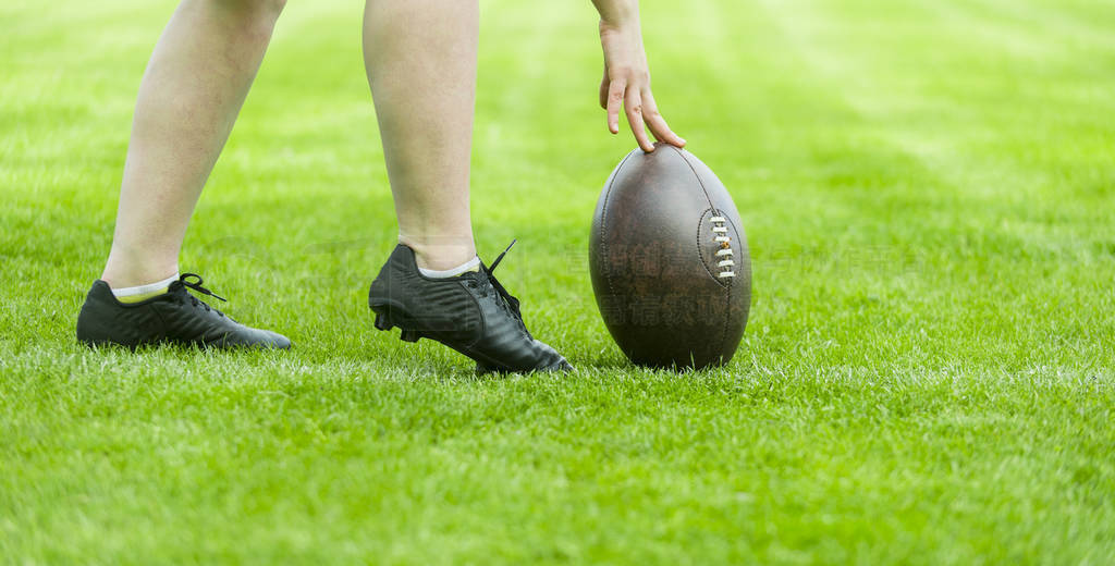 rugby ball with his feet on the grass field