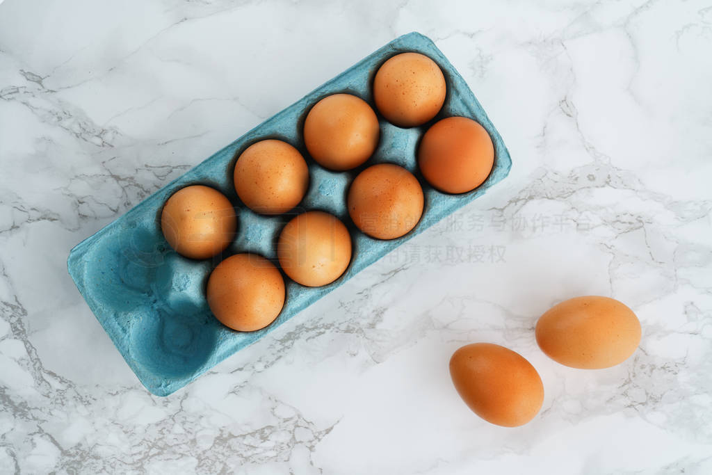 Close-up view of raw organic chicken eggs in a blue carton box.