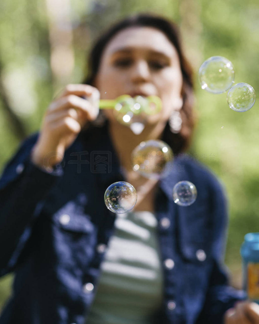 Careless pretty woman blowing soap bubbles outdoors