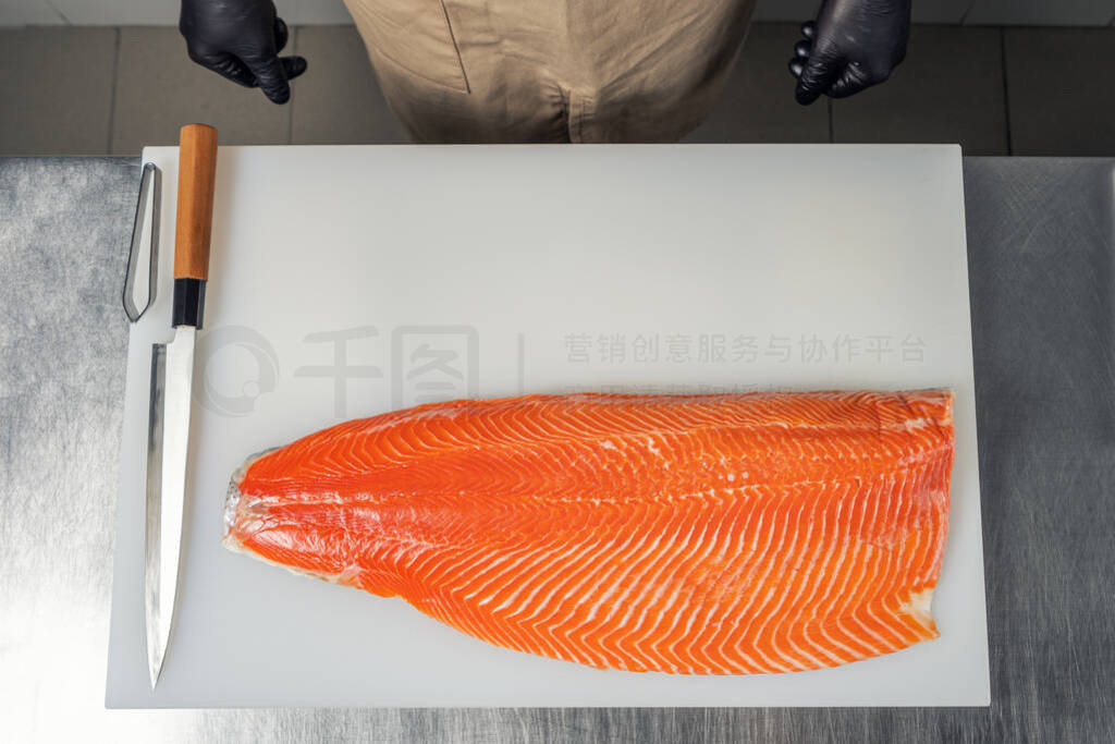 Salmon fillet on a white cutting Board near the knife and cook,