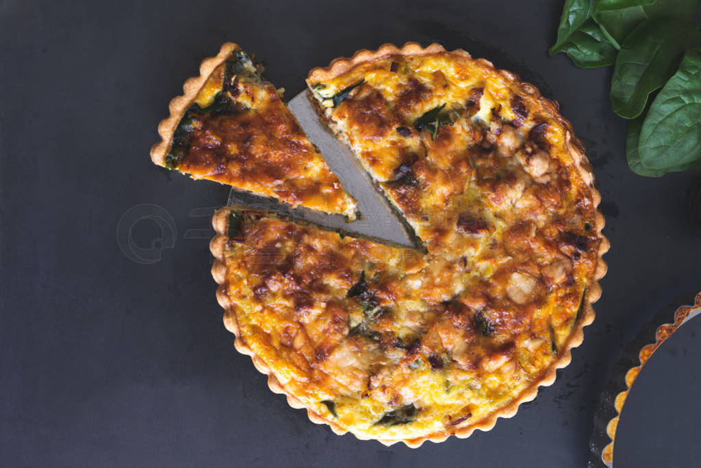 freshly bake leek bacon spinach quiche on dark blue background