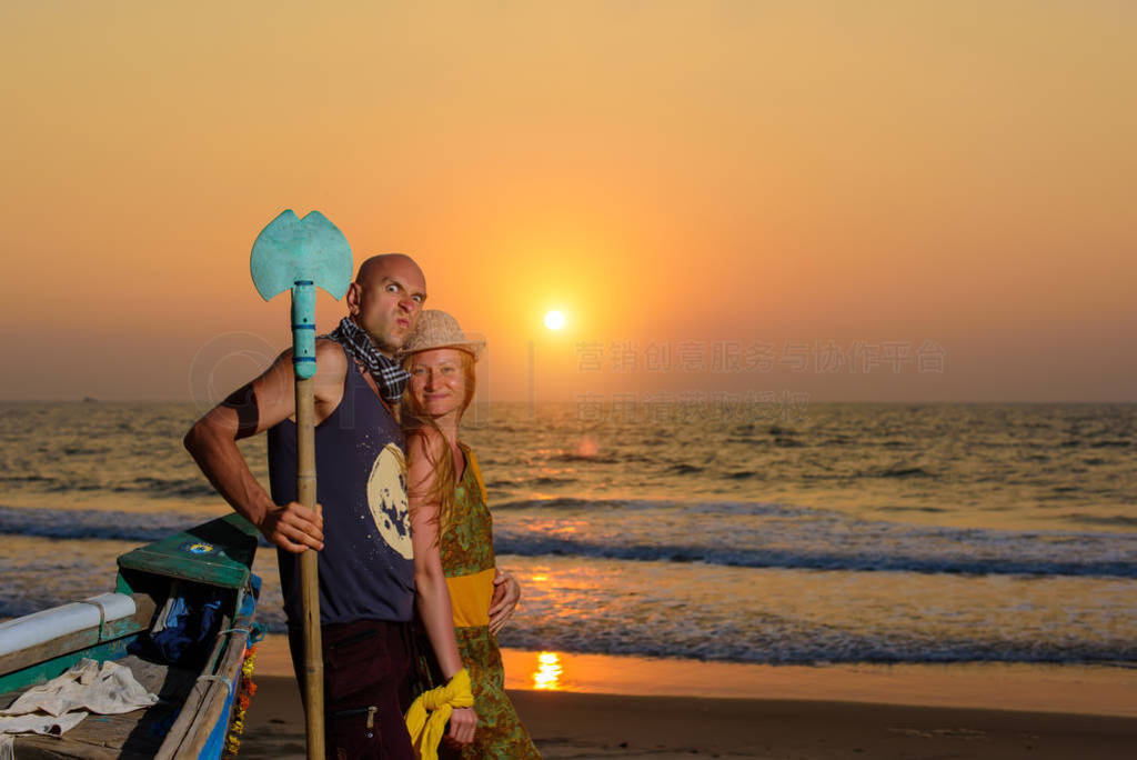 Young couple posing against sea at sunset. Guy and girl fooling