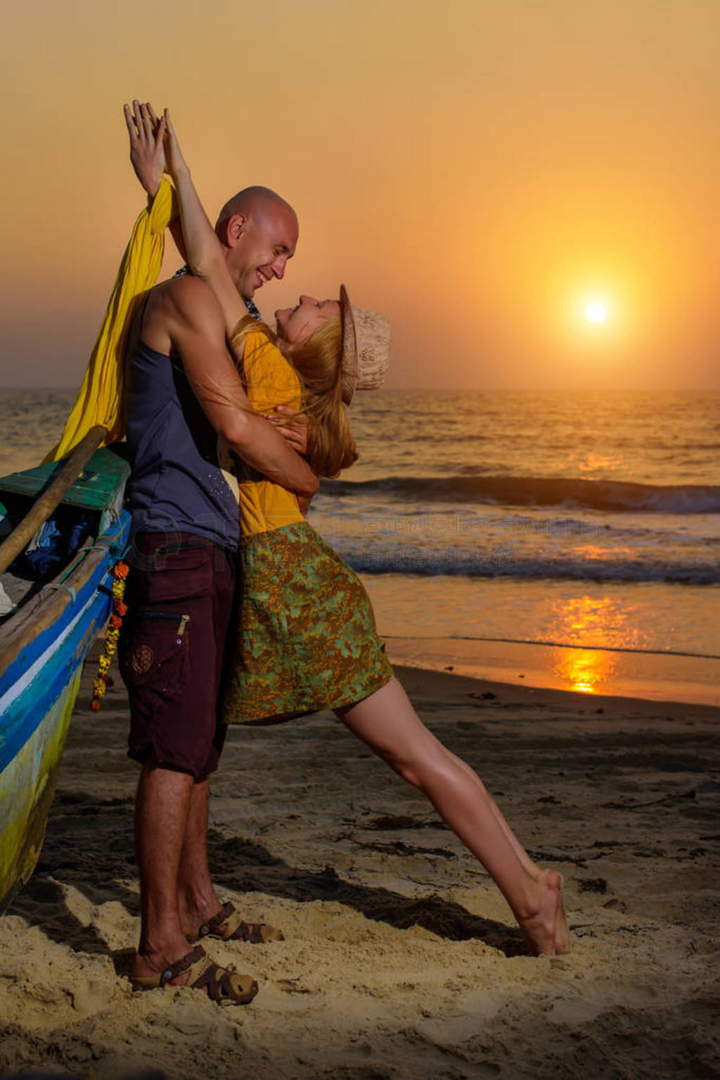 Young couple posing against sea at sunset. Guy and girl fooling