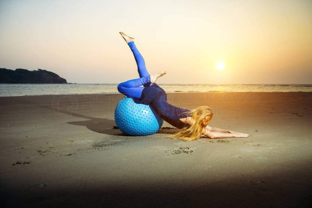 Flexible young girl with long blonde hair exercising on a yoga b