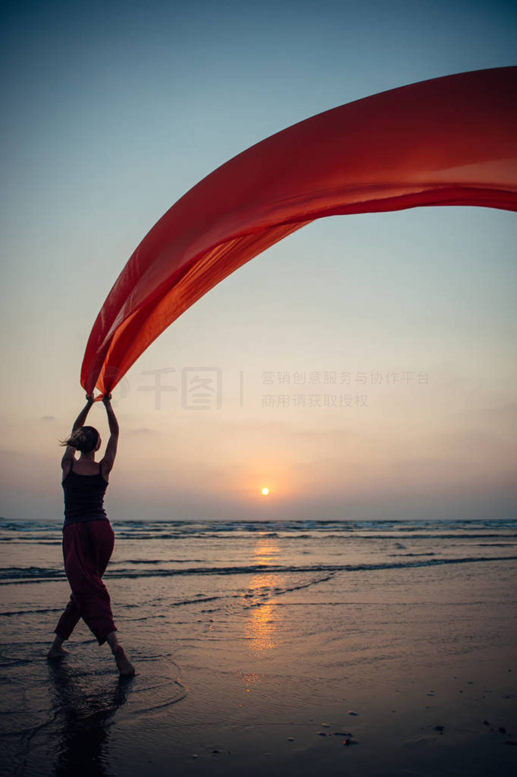 Elegant young girl performs dance moves on the sand holding a lo