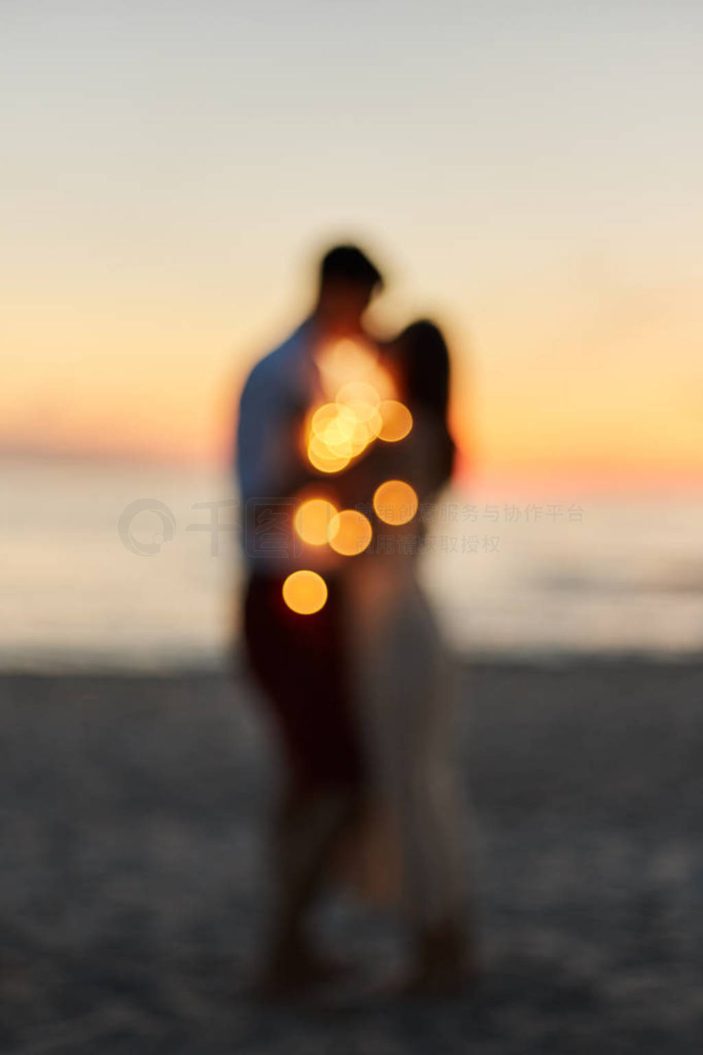 Silhouette of a young couple kissing on the seashore at sunset.